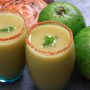 Spicy guava juice in two glasses garnished with mint leaf on top. Glass rim is dipped in salt and chili powder mixture
